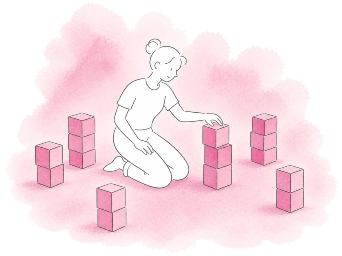 A kneeling volunteer stacks wooden cubes among several completed piles.