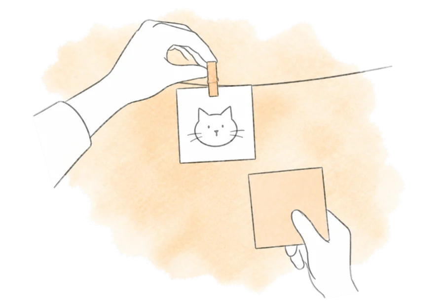 A hand pins a chosen cat photo onto a display line.