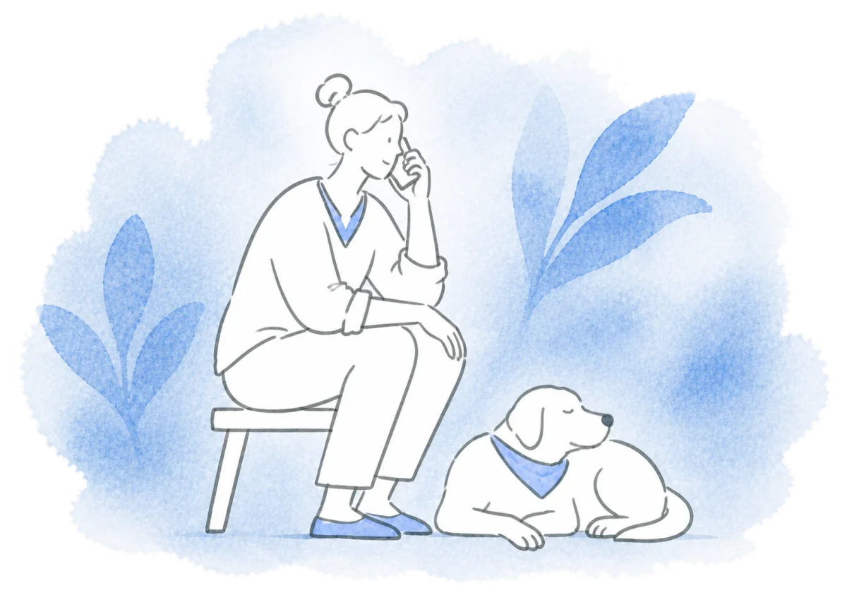 A volunteer speaks on the phone while a dog rests nearby.