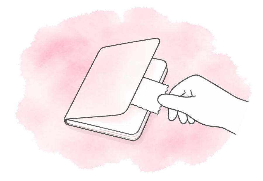 A hand slips a receipt into a small open notebook.