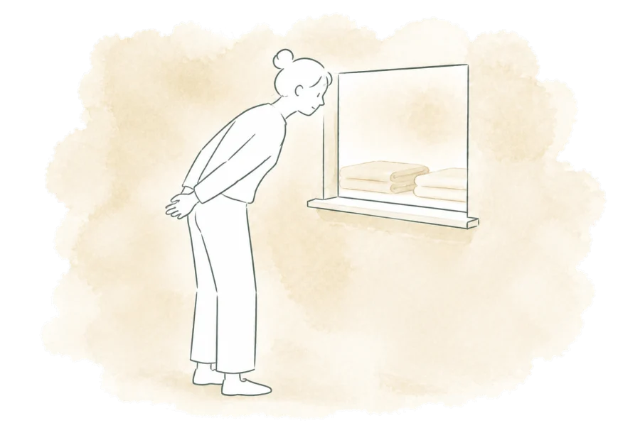 A volunteer looks through a window with their hands resting behind their back.